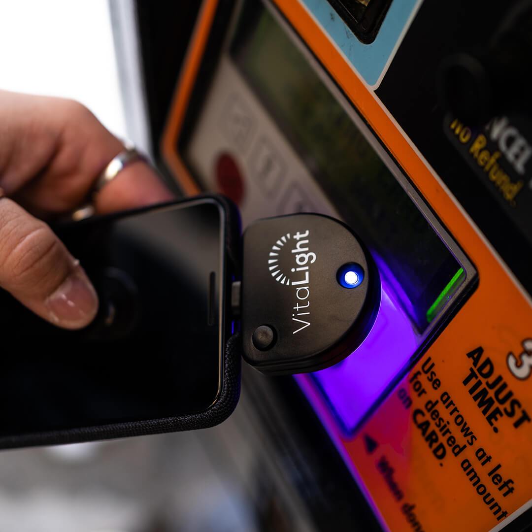 Portable UV sanitizing light wand cleaning dirty gas station button.